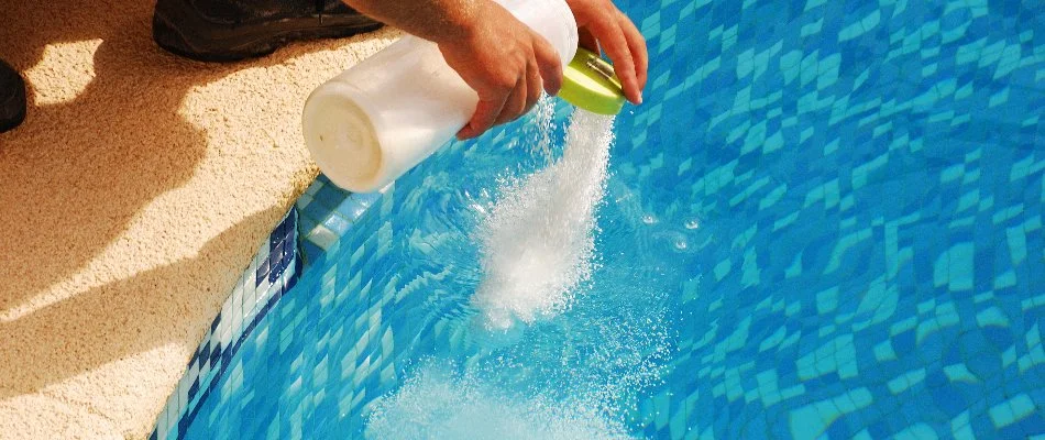 Worker adding chemicals to a pool in Bridgehampton, NY.