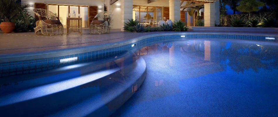 A luxury pool in the evening with pool lights at a home in Noyack, NY.