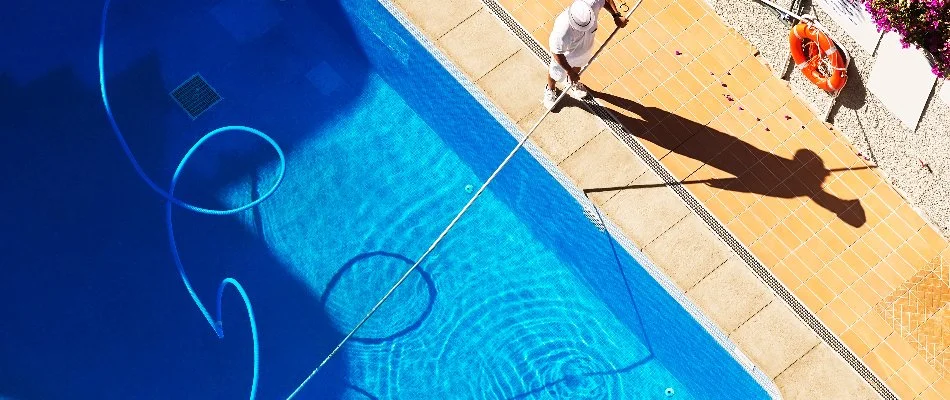 Worker in Bridgehampton, NY, cleaning a pool.