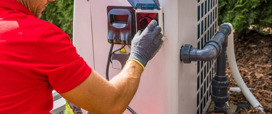 Worker installing a heat pump for a pool.