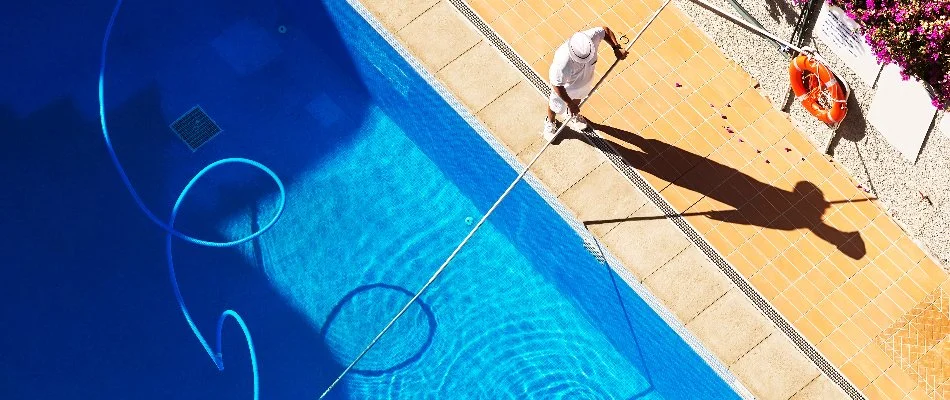 Worker in East Hampton, NY, cleaning a pool.