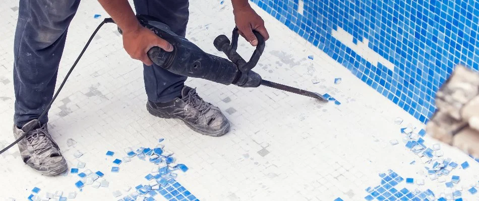 Worker in Bridgehampton, NY, removing tiles on a pool.